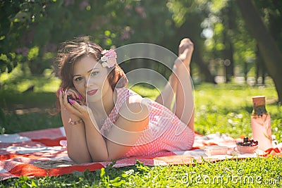 A charming young girl enjoys a rest and a picnic on the green summer grass alone. pretty woman have a holiday Stock Photo