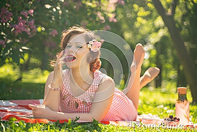 A charming young girl enjoys a rest and a picnic on the green summer grass alone. pretty woman have a holiday Stock Photo