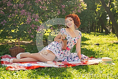 A charming young girl enjoys a rest and a picnic on the green summer grass alone. pretty woman have a holiday Stock Photo