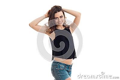 A charming young lady in a black t-shirt and denim shorts smiles and keeps hands hair Stock Photo