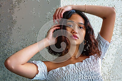 Charming young woman frames face with arms Stock Photo