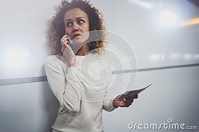 Charming young woman on transit talking on smartphone while holding with hand travel ticket in train station or airpot Stock Photo