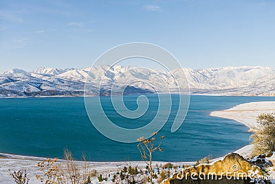 Charvak reservoir in Uzbekistan in winter with blue water in it, surrounded by the Tien Shan mountain system Stock Photo