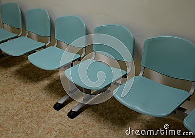 Cheap plastic chairs in a row by the wall. classic waiting room at the train station or at the doctor`s. corridor with washable su Stock Photo