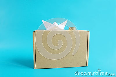 Cheap shipping cargo concept. Paper ship, coins and craft box front view isolated blue background Stock Photo