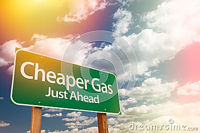 Cheaper Gas Green Road Sign Against Cloudy Sky Stock Photo