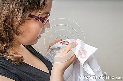 Cheating and infidelity concept. Jealousy young woman found red lipstick stains on shirt. Stock Photo