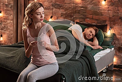 Girlfriend cheating on her man sleeping in bed while texting other man Stock Photo