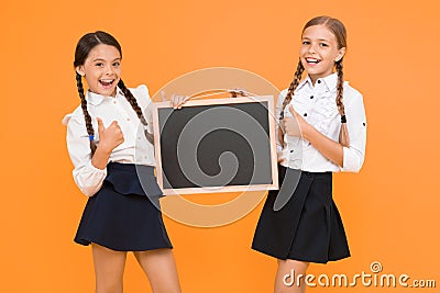 Check this out. School girls cute pupils hold blackboard copy space. Classmates initiative team yellow background. Join Stock Photo