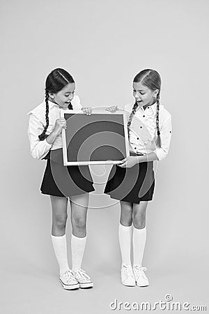 Check this out. School girls cute pupils hold blackboard copy space. Pupils community. Classmates initiative team yellow Stock Photo