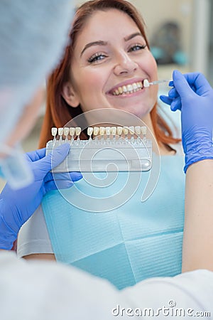 Check and select the color of the teeth in the dentist chair. Dentist makes the process of treating a beautiful young Stock Photo