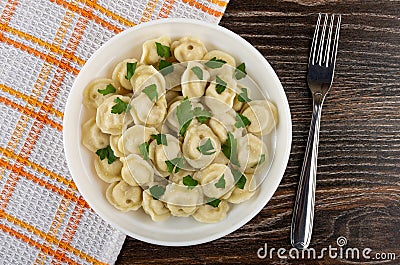 Napkin, meat dumplings with parsley in plate, fork on wooden table. Top view Stock Photo