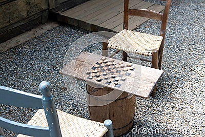 Checkers game made from wood and corn cob pieces on a barrel with chairs Stock Photo