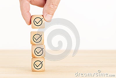 Checking or checklist concept. Hand picked wooden cube block with check icon. Copy space Stock Photo