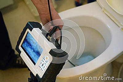 Checking clogged toilet pipe with inspection camera. Stock Photo