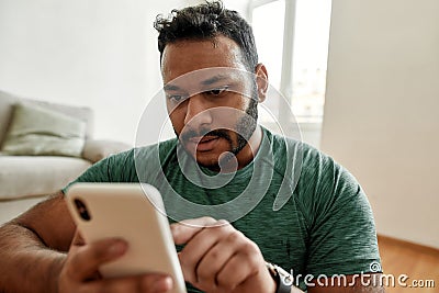 Checking. Close up of young man using smartphone app while having morning workout at home. Freshman relaxing after Stock Photo