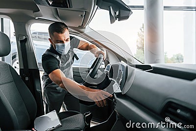 Checking control panel. Man in uniform is working in the autosalon at daytime Stock Photo