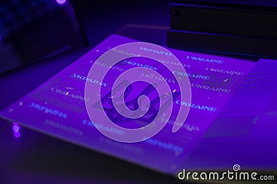Checking the passport for fraud in UV light, detection of luminescence of protective components of the document threads, melange Stock Photo