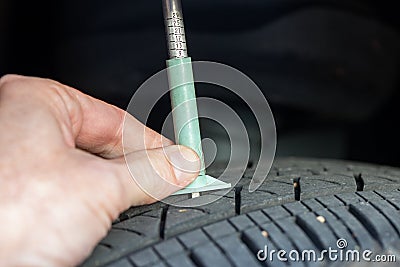 Checking tread depth on a tire with a tire gauge Stock Photo