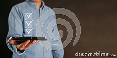 Checklist concept. A man with a tablet checks digital correct marks on the checkboxes. Smart performance monitoring, online survey Stock Photo