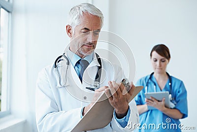 Checklist, research or mature doctor writing medical notes, feedback review or schedule in hospital. Clipboard Stock Photo