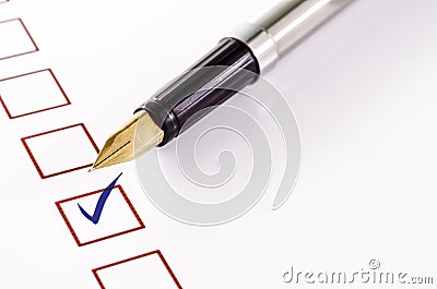Checklist with a ticked box and a pen on white paper. Stock Photo