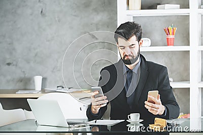 Cheeky businessman using two smartphones Stock Photo