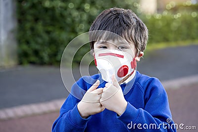 Cheer up kid wearing protective face mask for pollution or virus, Child in school uniform wearing medical face mask and showing Stock Photo