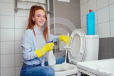 Cheereful redhaired ginger woman washing in rest room toilet wearing gloves Stock Photo