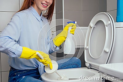 Cheereful redhaired ginger woman washing in rest room toilet wearing gloves Stock Photo