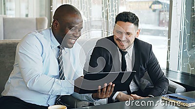Cheerful African American businessman in formal clothes using digital tablet discussing startup project with his stock video footage Cheerful African American businessman in formal clothes using digital tablet discussing startup project with his stock video footage