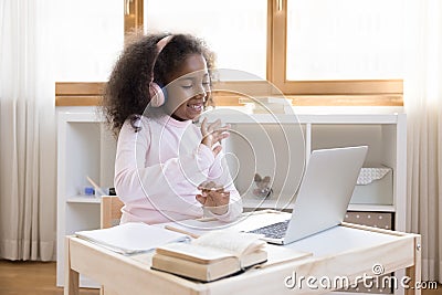 Cheerful African American little blogger girl wearing wireless pink headphones Stock Photo