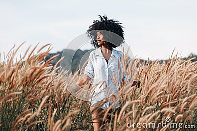 Cheerful african american young woman on the field at sunset Stock Photo