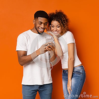 Cheerful african man and woman listening to music on cellphone Stock Photo