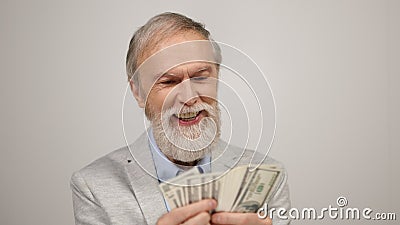 Cheerful aged man holding money indoors. Old guy having fun in modern studio. Stock Photo