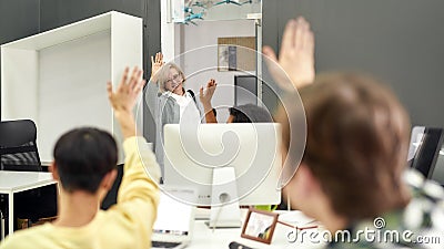 Cheerful aged woman, senior intern waving, saying goodbye to her young colleagues while leaving office after first day Stock Photo