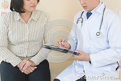 Cheerful Asian doctor talking with young woman patient for monitoring. Stock Photo