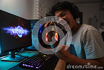 Cheerful asian gamer boy rejoicing victory while playing video g Stock Photo