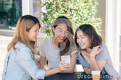 Cheerful asian young women sitting in cafe drinking coffee with friends and talking together. Stock Photo