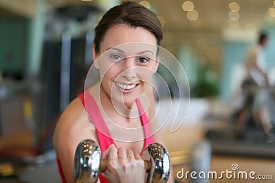 Cheerful athletic woman lifting dumbbells in a fitness center Stock Photo