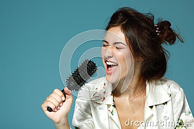 Cheerful attractive teen girl sing song holding comb like a micr Stock Photo