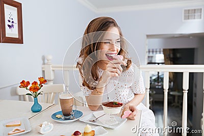 Cheerful attractive young woman sitting and eating heart shaped cookies Stock Photo