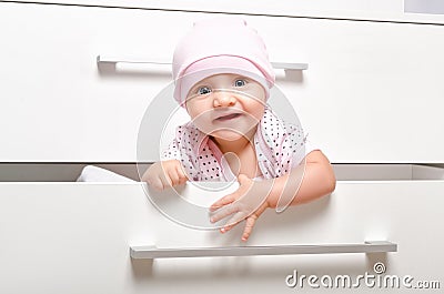 Cheerful baby looking out of the the chest of drawers Stock Photo