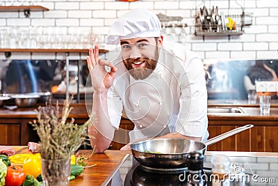 Cheerful bearded chef cook cooking and showing ok sign Stock Photo