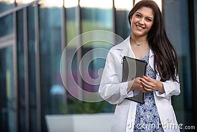 Cheerful beautiful brunette medical student or intern at dental, psychiatry, pharmaceutical job, smiling with electronic tablet Stock Photo