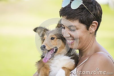 Cheerful beautiful caucasian woman carying a nice pet shetland dog with love and friendship. best friends forever concept with Stock Photo