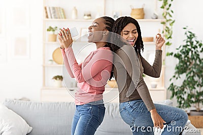 Cheerful black girlfriends singing and dancing at home Stock Photo