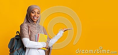 Cheerful black islamic female student in hijab pointing aside with hand Stock Photo