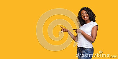 Cheerful black lady pointing at copy space on yellow Stock Photo