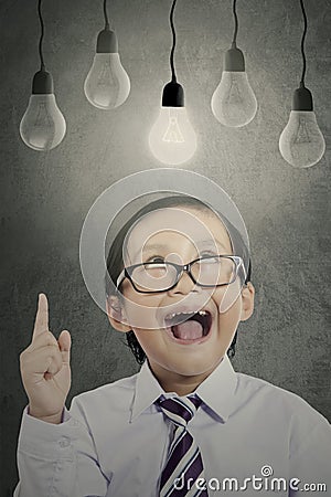 Cheerful boy with bright bulb on classroom Stock Photo